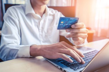 Genç adam, laptop bilgisayar başvurusu ya da web sitesinde online alışveriş yapmak için kredi kartı kullanıyor. E-ticaret ve online alışveriş kavramı.