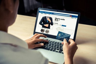 Genç adam, laptop bilgisayar başvurusu ya da web sitesinde online alışveriş yapmak için kredi kartı kullanıyor. E-ticaret ve online alışveriş kavramı.