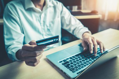 Genç adam, laptop bilgisayar başvurusu ya da web sitesinde online alışveriş yapmak için kredi kartı kullanıyor. E-ticaret ve online alışveriş kavramı.