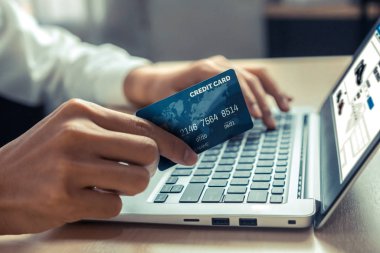 Genç adam, laptop bilgisayar başvurusu ya da web sitesinde online alışveriş yapmak için kredi kartı kullanıyor. E-ticaret ve online alışveriş kavramı.