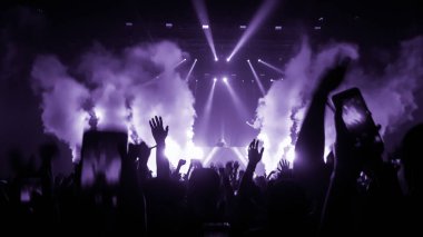 Mutlu insanlar gece kulübü DJ parti konserinde dans eder ve sahnede DJ 'den elektronik dans müziği dinlerler. Siluet dolu neşeli kalabalık 2020 yılbaşı partisini kutluyor. İnsanların yaşam tarzı DJ gece hayatı.