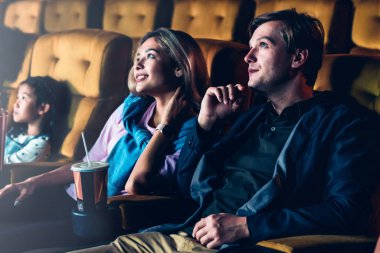 Bir çift ve çocuklar sinemada film izlemekten zevk alıyorlar.