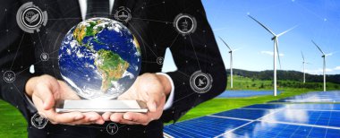 Alternatif enerji ile sürdürülebilirlik gelişimi kavramı. Çevre dostu rüzgar türbini çiftliği ve arka planda yeşil yenilenebilir enerji ile insan eliyle dünya ile ilgilenin..