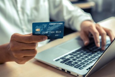 Genç adam, laptop bilgisayar başvurusu ya da web sitesinde online alışveriş yapmak için kredi kartı kullanıyor. E-ticaret ve online alışveriş kavramı.