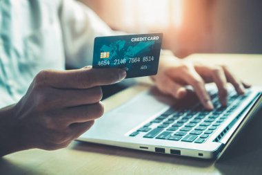 Genç adam, laptop bilgisayar başvurusu ya da web sitesinde online alışveriş yapmak için kredi kartı kullanıyor. E-ticaret ve online alışveriş kavramı.
