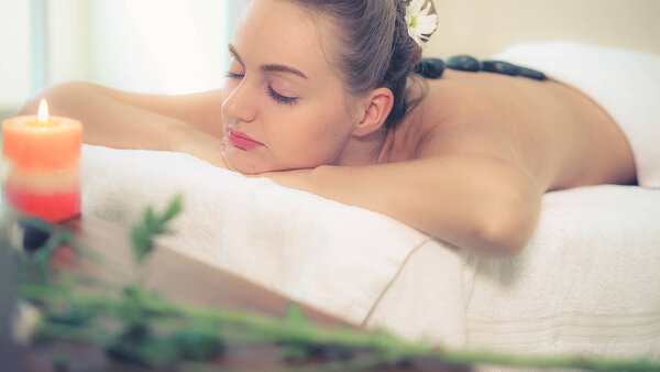 Женщина получает массаж горячими камнями от профессионального косметолога в спа-салоне. Концепция роскошного wellness, снятия стресса и восстановления сил.