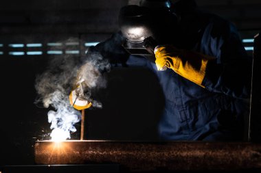 Fabrikada çelik kaynak makinesiyle çalışan metal kaynakçı güvenlik ekipmanı takıyor. El becerisi iş gücü kavramına göre metal imalatı ve inşaat bakım hizmeti.