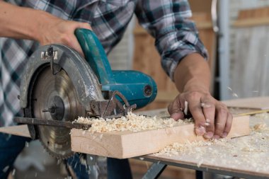 Marangoz atölyede ahşap işçiliği yapıyor. İnşaat malzemesi ya da ahşap mobilya üretiyor. Genç Asyalı marangoz zanaat için profesyonel araçlar kullanır. DIY üreticisi ve marangozluk konsepti.