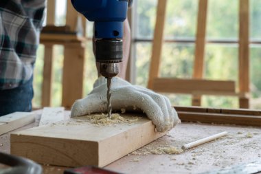 Marangoz atölyede ahşap işçiliği yapıyor. İnşaat malzemesi ya da ahşap mobilya üretiyor. Genç Asyalı marangoz zanaat için profesyonel araçlar kullanır. DIY üreticisi ve marangozluk konsepti.