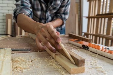 Marangoz atölyede ahşap işçiliği yapıyor. İnşaat malzemesi ya da ahşap mobilya üretiyor. Genç Asyalı marangoz zanaat için profesyonel araçlar kullanır. DIY üreticisi ve marangozluk konsepti.