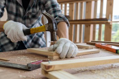 Marangoz atölyede ahşap işçiliği yapıyor. İnşaat malzemesi ya da ahşap mobilya üretiyor. Genç Asyalı marangoz zanaat için profesyonel araçlar kullanır. DIY üreticisi ve marangozluk konsepti.