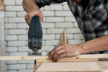 Marangoz atölyede ahşap işçiliği yapıyor. İnşaat malzemesi ya da ahşap mobilya üretiyor. Genç Asyalı marangoz zanaat için profesyonel araçlar kullanır. DIY üreticisi ve marangozluk konsepti.
