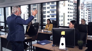 Kıdemli lider takım üyelerine tavsiye konuşması yapıyor. Modern ofisteki masada yaratıcı iş adamları buluşuyor. Çok kültürlü iş ekibi..