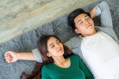 Mutlu Asyalı çift oturma odasının zemininde birlikte yatıyorlar. Aşk ilişkisi ve yaşam tarzı kavramı.