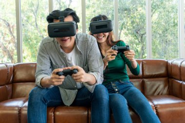 Genç mutlu Asyalı çift oturma odasında video oyunu oynuyor. Neşeli insanlar bilgisayar oyunu konseptiyle eğleniyor..