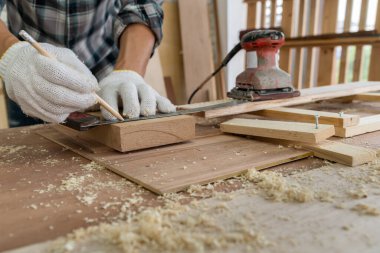 Marangoz atölyede ahşap işçiliği yapıyor. İnşaat malzemesi ya da ahşap mobilya üretiyor. Genç Asyalı marangoz zanaat için profesyonel araçlar kullanır. DIY üreticisi ve marangozluk konsepti.