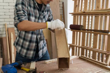 Marangoz atölyede ahşap işçiliği yapıyor. İnşaat malzemesi ya da ahşap mobilya üretiyor. Genç Asyalı marangoz zanaat için profesyonel araçlar kullanır. DIY üreticisi ve marangozluk konsepti.