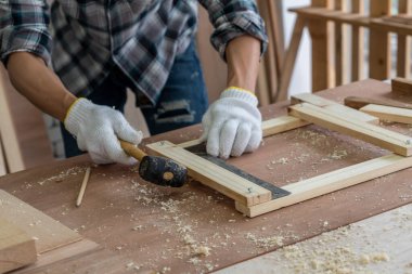 Marangoz atölyede ahşap işçiliği yapıyor. İnşaat malzemesi ya da ahşap mobilya üretiyor. Genç Asyalı marangoz zanaat için profesyonel araçlar kullanır. DIY üreticisi ve marangozluk konsepti.