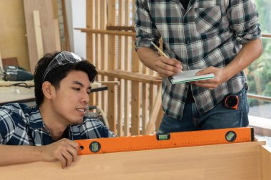 Marangoz atölyede ahşap işçiliği yapıyor. İnşaat malzemesi ya da ahşap mobilya üretiyor. Genç Asyalı marangoz zanaat için profesyonel araçlar kullanır. DIY üreticisi ve marangozluk konsepti.