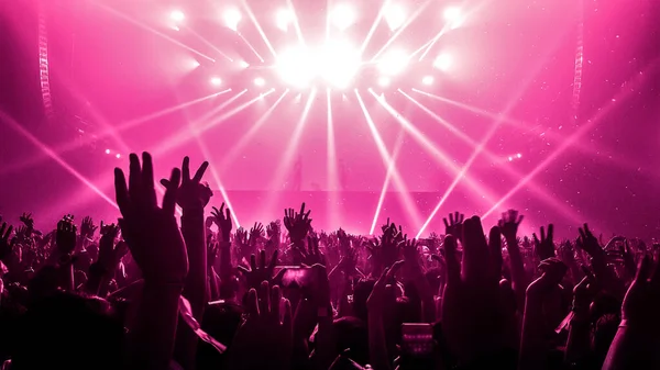 Happy people dance in nightclub DJ party concert and listen to electronic dancing music from DJ on the stage. Silhouette cheerful crowd celebrate New Year party 2020. People lifestyle DJ nightlife.