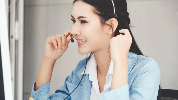 Customer support agent or call center with headset works on desktop computer while supporting the customer on phone call. Operator service business representative concept.