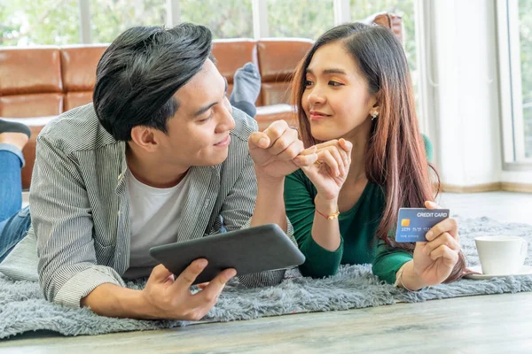 Young couple use credit card for online shopping on internet website at home. Number on the credit card is mock up. No personal information shown on the credit card. Online business shopping concept.