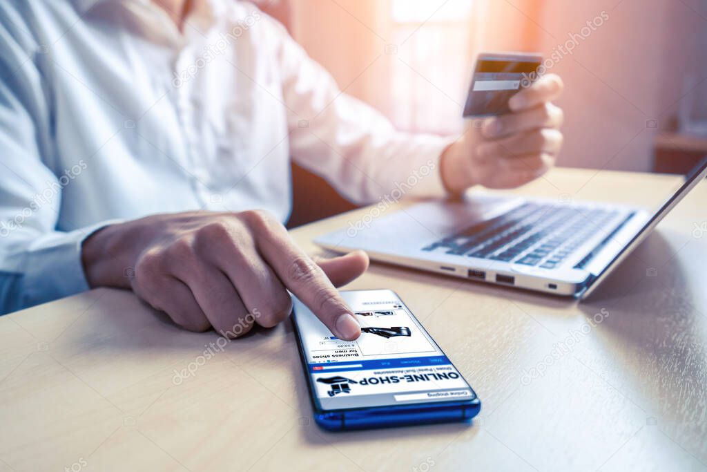 Young man use credit card for shopping payment online on laptop computer application or website. E-commerce and online shopping concept.