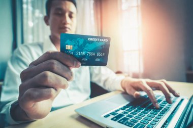 Genç adam, laptop bilgisayar başvurusu ya da web sitesinde online alışveriş yapmak için kredi kartı kullanıyor. E-ticaret ve online alışveriş kavramı.