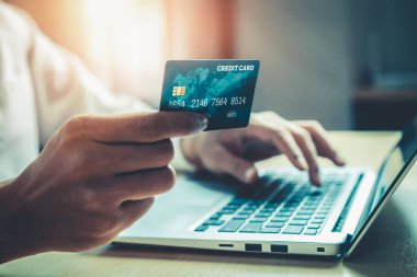 Genç adam, laptop bilgisayar başvurusu ya da web sitesinde online alışveriş yapmak için kredi kartı kullanıyor. E-ticaret ve online alışveriş kavramı.