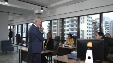 Kıdemli lider takım üyelerine tavsiye konuşması yapıyor. Modern ofisteki masada yaratıcı iş adamları buluşuyor. Çok kültürlü iş ekibi..