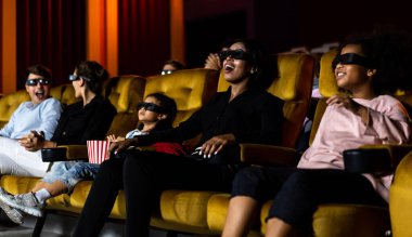 Bir grup insan, sinemada 3D gözlüklü bir film izliyor. Ekrana bakıyor, heyecan verici ve eğleniyor.