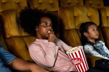 Üç çocuk eğleniyor ve sinemada film izlemekten zevk alıyor.