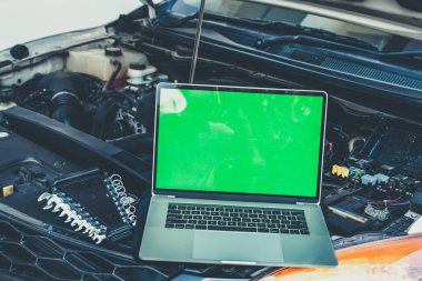 Motor kontrolü için arabanın kaputunda dizüstü bilgisayar var. Garaj tamiri konsepti.