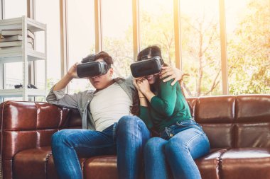 Evdeki oturma odasında sanal gerçeklikte video izleyen mutlu çift. Multimedya film ve eğlence konsepti.