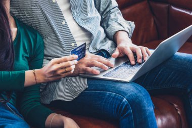 Genç çift evdeki internet sitesinden online alışveriş için kredi kartını kullanıyor. Kredi kartındaki numara sahte. Kredi kartında kişisel bilgi yok. Çevrimiçi iş alışveriş kavramı.