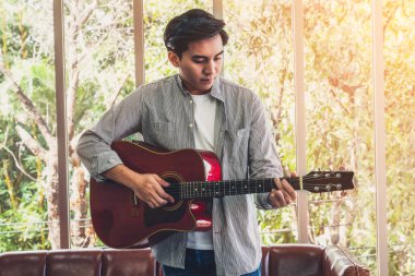 Genç gitarist gitarını evde tutuyor. Müzik ve şarkı konsepti.