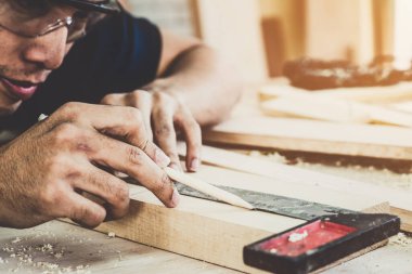Marangoz atölyede ahşap işçiliği yapıyor. İnşaat malzemesi ya da ahşap mobilya üretiyor. Genç Asyalı marangoz zanaat için profesyonel araçlar kullanır. DIY üreticisi ve marangozluk konsepti.