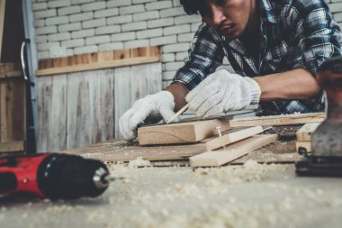 Marangoz atölyede ahşap işçiliği yapıyor. İnşaat malzemesi ya da ahşap mobilya üretiyor. Genç Asyalı marangoz zanaat için profesyonel araçlar kullanır. DIY üreticisi ve marangozluk konsepti.