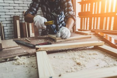 Marangoz atölyede ahşap işçiliği yapıyor. İnşaat malzemesi ya da ahşap mobilya üretiyor. Genç Asyalı marangoz zanaat için profesyonel araçlar kullanır. DIY üreticisi ve marangozluk konsepti.