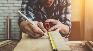 Marangoz atölyede ahşap işçiliği yapıyor. İnşaat malzemesi ya da ahşap mobilya üretiyor. Genç Asyalı marangoz zanaat için profesyonel araçlar kullanır. DIY üreticisi ve marangozluk konsepti.