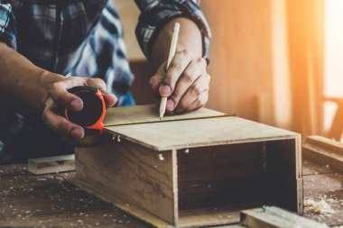 Marangoz atölyede ahşap işçiliği yapıyor. İnşaat malzemesi ya da ahşap mobilya üretiyor. Genç Asyalı marangoz zanaat için profesyonel araçlar kullanır. DIY üreticisi ve marangozluk konsepti.
