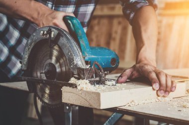 Marangoz atölyede ahşap işçiliği yapıyor. İnşaat malzemesi ya da ahşap mobilya üretiyor. Genç Asyalı marangoz zanaat için profesyonel araçlar kullanır. DIY üreticisi ve marangozluk konsepti.