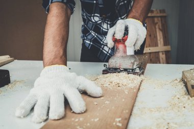 Marangoz atölyede ahşap işçiliği yapıyor. İnşaat malzemesi ya da ahşap mobilya üretiyor. Genç Asyalı marangoz zanaat için profesyonel araçlar kullanır. DIY üreticisi ve marangozluk konsepti.