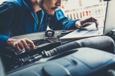 Oto tamirhanesinde araba tamiri ve bakım hizmeti veren profesyonel bir tamirci. Araba servisi iş konsepti.