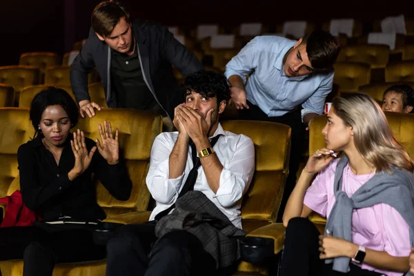 Annoying man talking on the mobile phone at the movie theater people in cinema is angry him