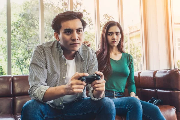 Young Asian couple suffers from computer games addiction. Family problem concept.