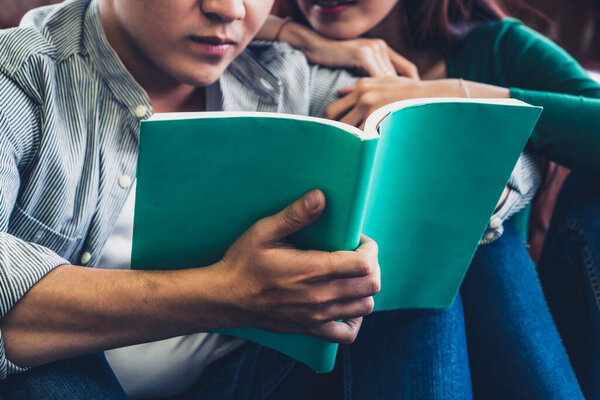 Young Asian couple reading book in living room. Love relationship and lifestyle concept.