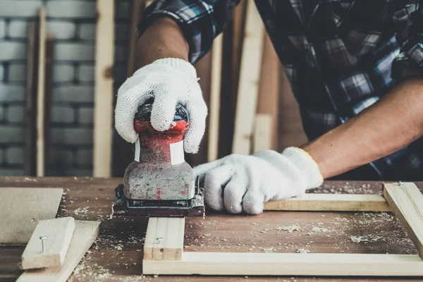 Carpenter working on wood craft at workshop to produce construction material or wooden furniture. The young Asian carpenter use professional tools for crafting. DIY maker and carpentry work concept.