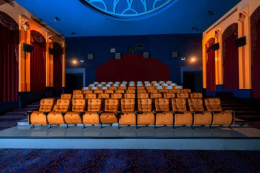 Sinema salonunun içi, sinematograf projektörüyle izleyicilerin izlediği koltuklarla dolu. Sinema klasik olarak dekore edilmiştir. Lüks sinema izleme hissi için..