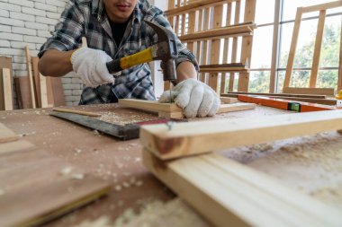 Marangoz atölyede ahşap işçiliği yapıyor. İnşaat malzemesi ya da ahşap mobilya üretiyor. Genç Asyalı marangoz zanaat için profesyonel araçlar kullanır. DIY üreticisi ve marangozluk konsepti.